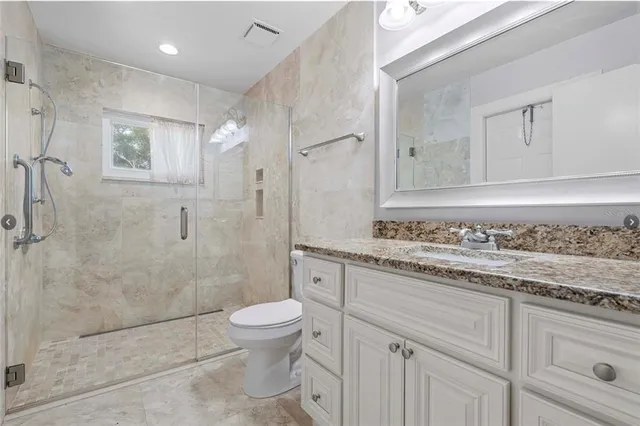 a bathroom with a granite countertop sink a toilet and shower