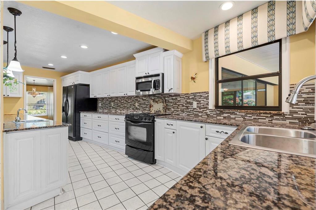 1255 Wisper Run Court Lutz, FL 33558 - Photo 7 of 25 a large kitchen with stainless steel appliances kitchen island granite countertop a sink and cabinets