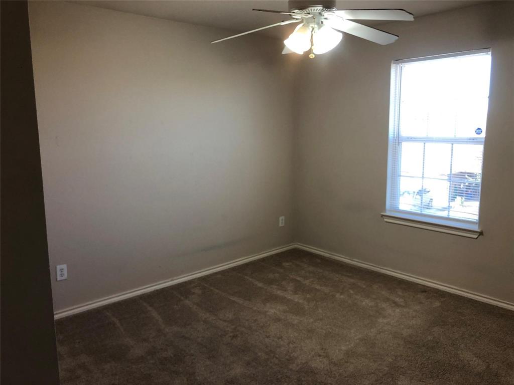921 Parkplace Ridge Princeton, TX 75407 - Photo 11 of 12 an empty room with a chandelier fan and windows