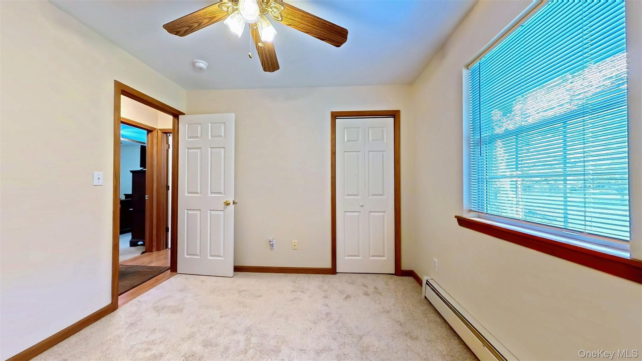 125 White Bridge Road Middletown, NY 10940 - Photo 32 of 43 Unfurnished bedroom featuring baseboard heating, light carpet, ceiling fan, and a closet