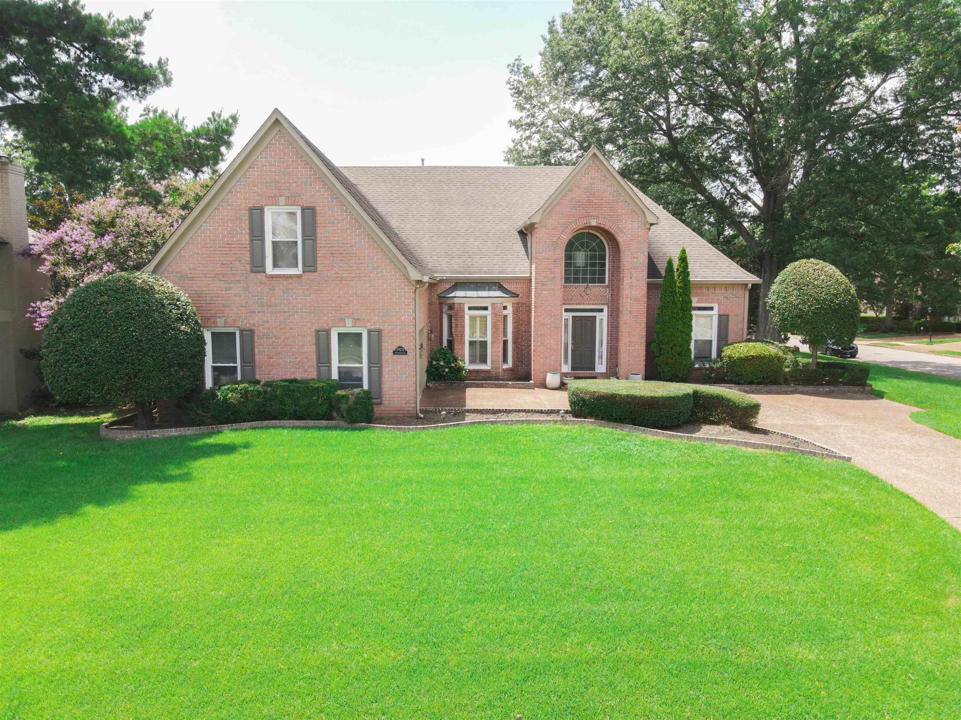 Traditional-style house featuring brick siding, a front lawn, and concrete driveway
