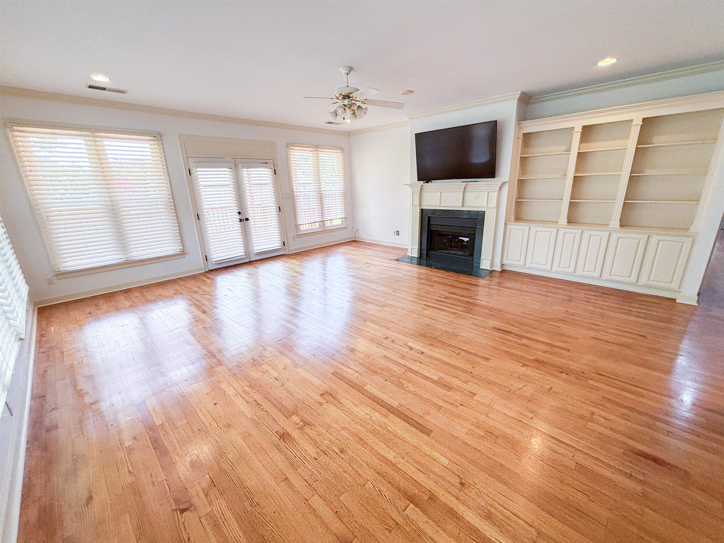 1923 Swynford Lane Collierville, TN 38017 - Photo 11 of 35 Unfurnished living room with crown molding, ceiling fan, a fireplace with flush hearth, and light wood-type flooring