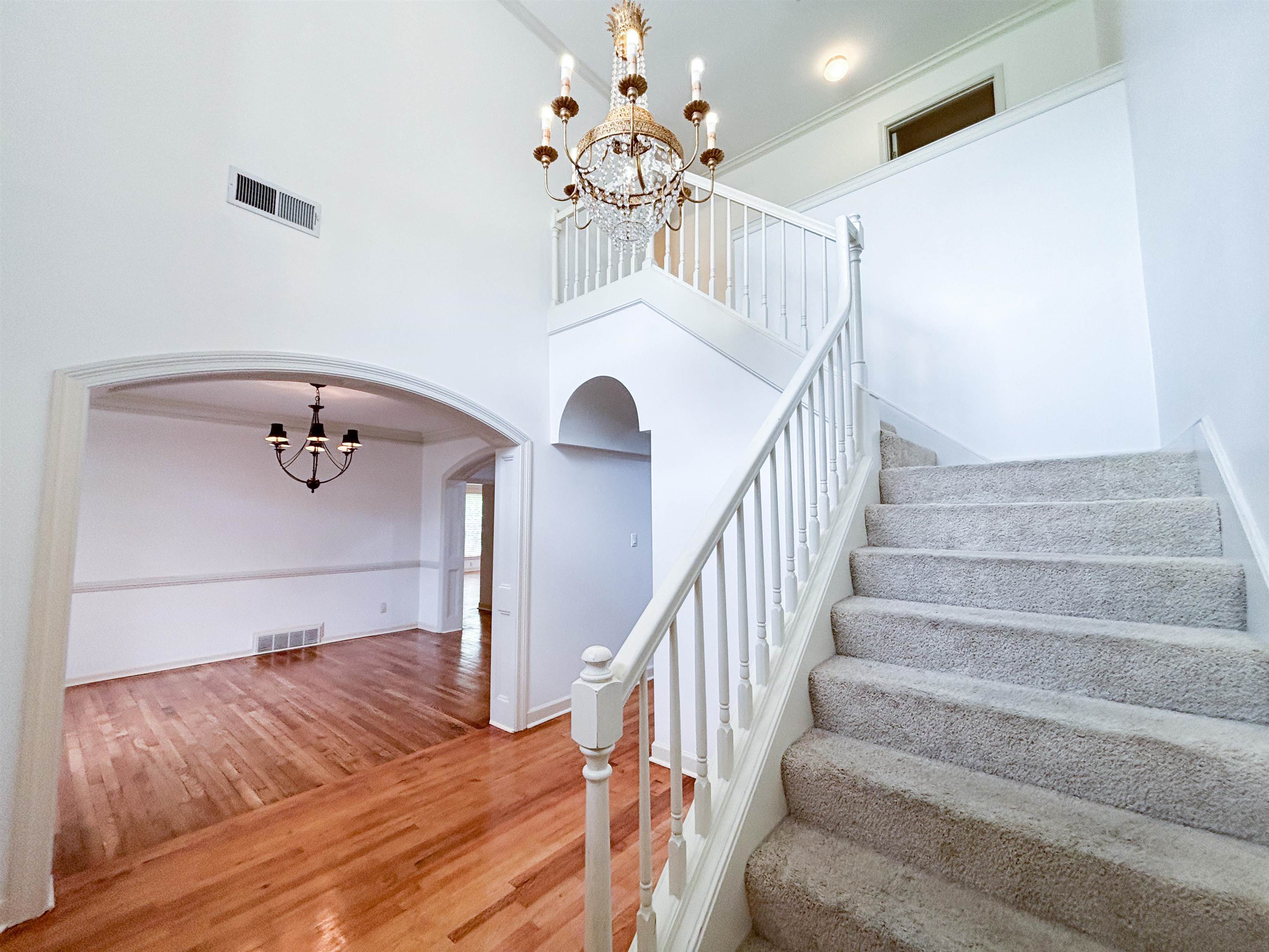 1923 Swynford Lane Collierville, TN 38017 - Photo 3 of 35 Stairs featuring a chandelier, arched walkways, wood finished floors, and a high ceiling