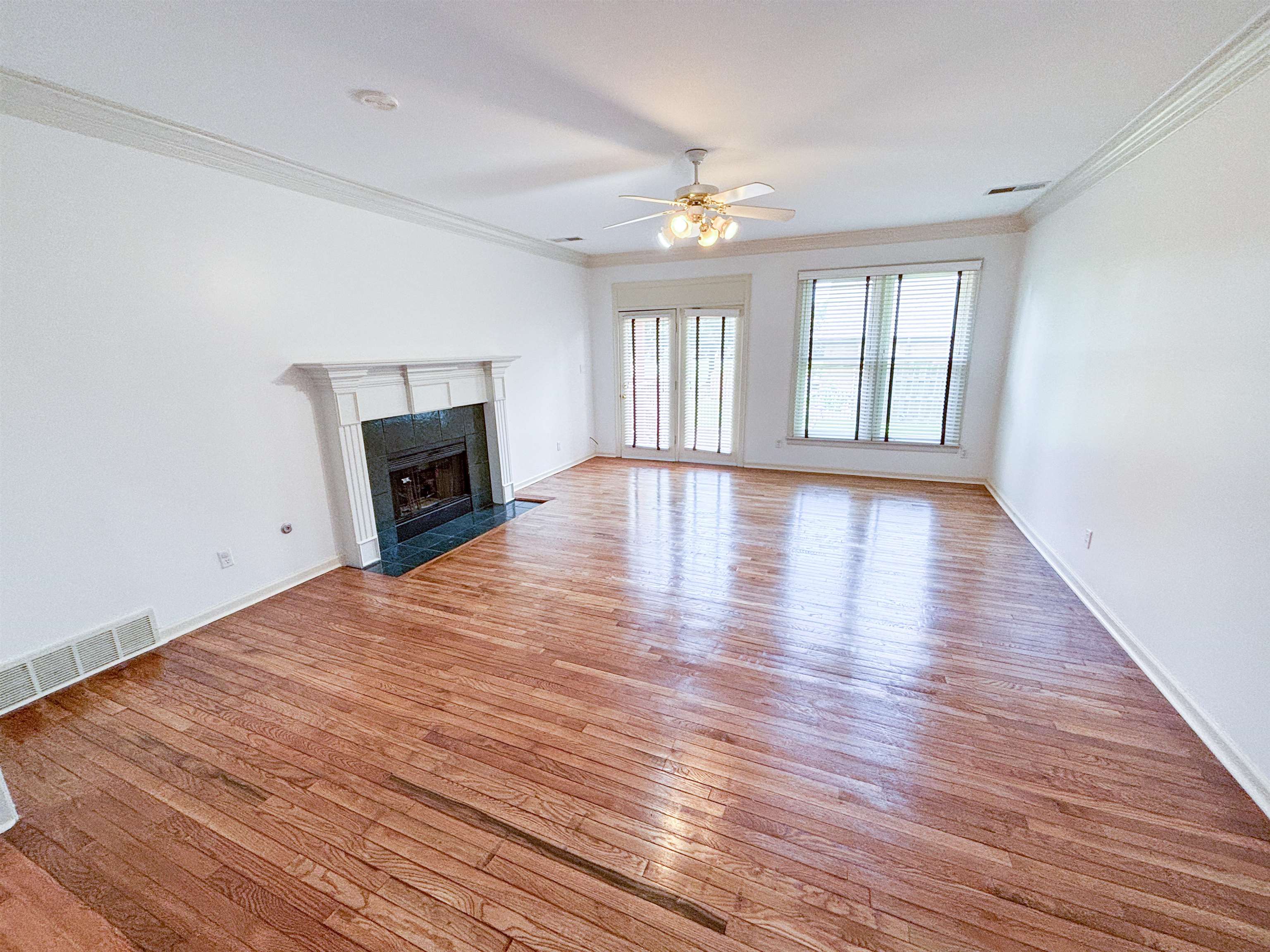 1923 Swynford Lane Collierville, TN 38017 - Photo 7 of 35 Unfurnished living room with crown molding, a ceiling fan, light wood-style flooring, and a tiled fireplace