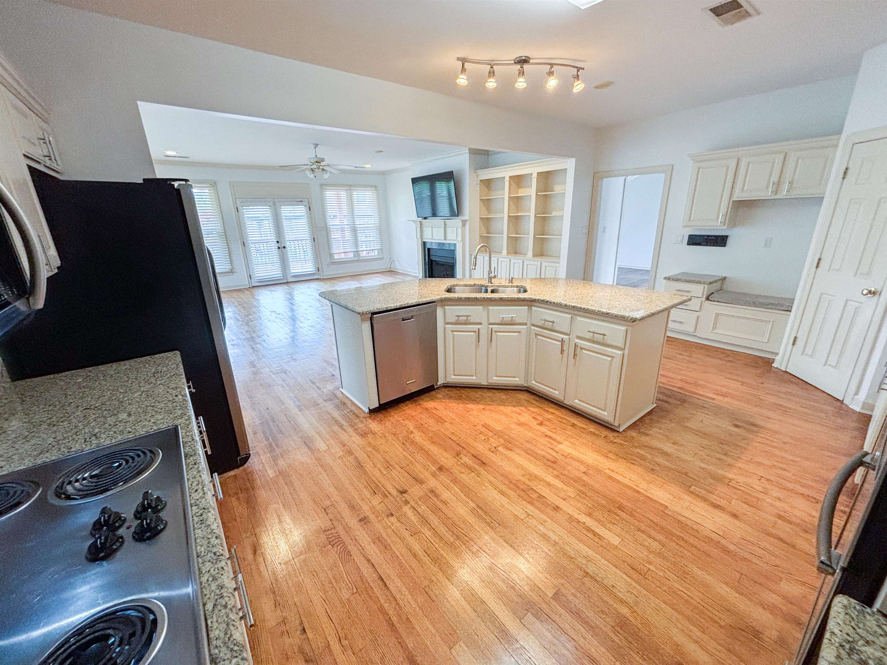 1923 Swynford Lane Collierville, TN 38017 - Photo 9 of 35 Kitchen with a fireplace, light wood-type flooring, a ceiling fan, white cabinetry, and stainless steel appliances