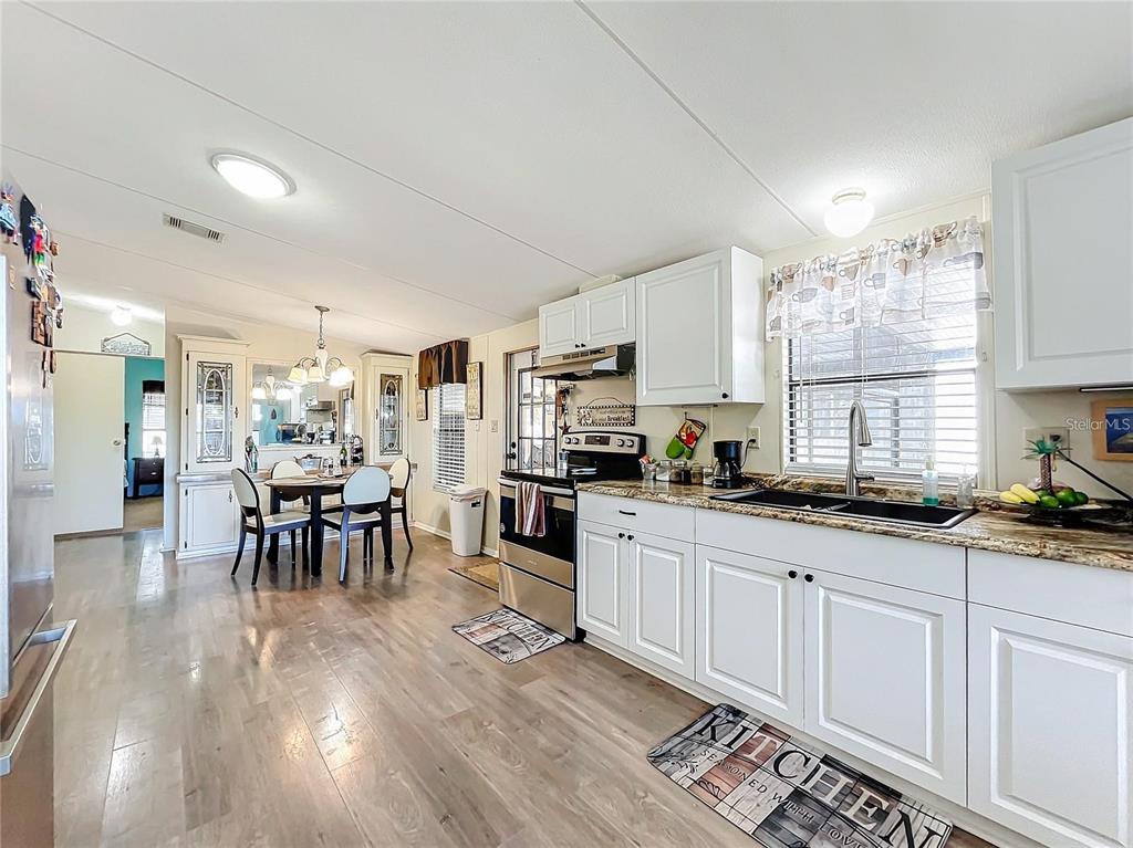 6 Cayman Circle Umatilla, FL 32784 - Photo 7 of 34 a kitchen with granite countertop a stove a sink a dining table and chairs