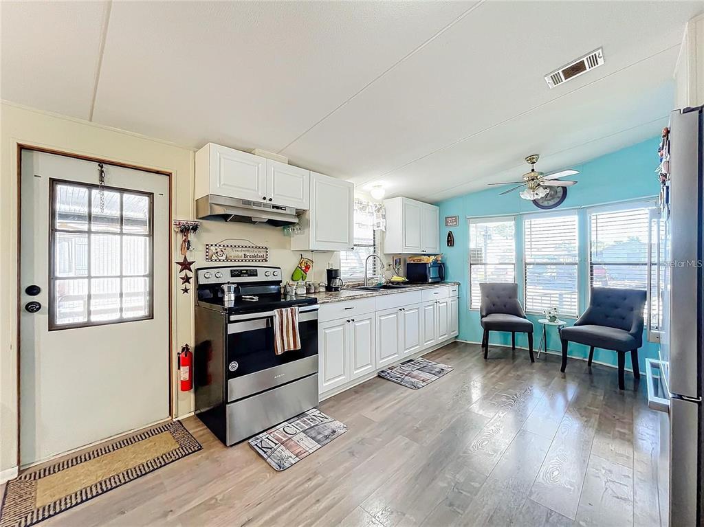 6 Cayman Circle Umatilla, FL 32784 - Photo 9 of 34 a kitchen with stainless steel appliances kitchen island wooden floors and white cabinets