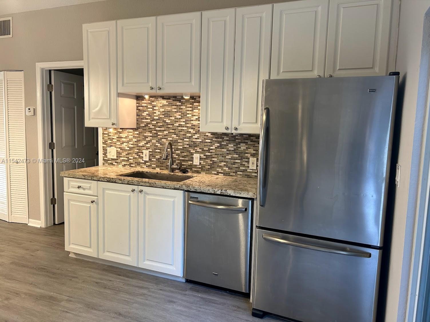 4802 Washington Street, Unit 5 Hollywood, FL 33021 - Photo 5 of 20 a kitchen with stainless steel appliances granite countertop a refrigerator sink and cabinets