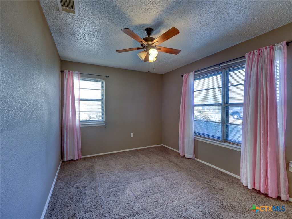 103 Lackey Street Florence, TX 76527 - Photo 24 of 39 an empty room with windows and ceiling fan