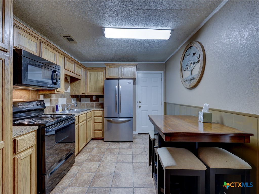103 Lackey Street Florence, TX 76527 - Photo 32 of 39 a kitchen with stainless steel appliances granite countertop a stove refrigerator and a microwave oven