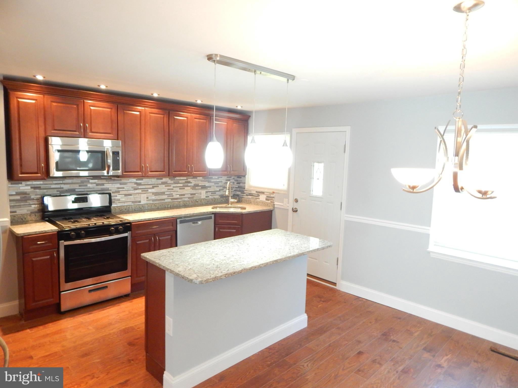 5618 Clearspring Road Baltimore, MD 21212 - Photo 7 of 30 a large kitchen with stainless steel appliances kitchen island granite countertop a stove a sink and a refrigerator