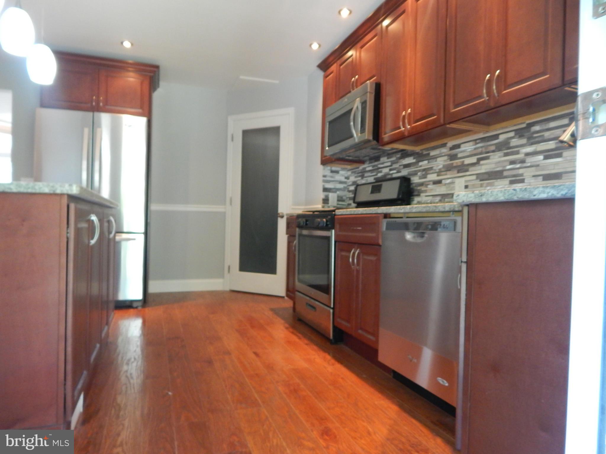5618 Clearspring Road Baltimore, MD 21212 - Photo 8 of 30 a kitchen with stainless steel appliances granite countertop a refrigerator a stove a sink and dishwasher with wooden floor
