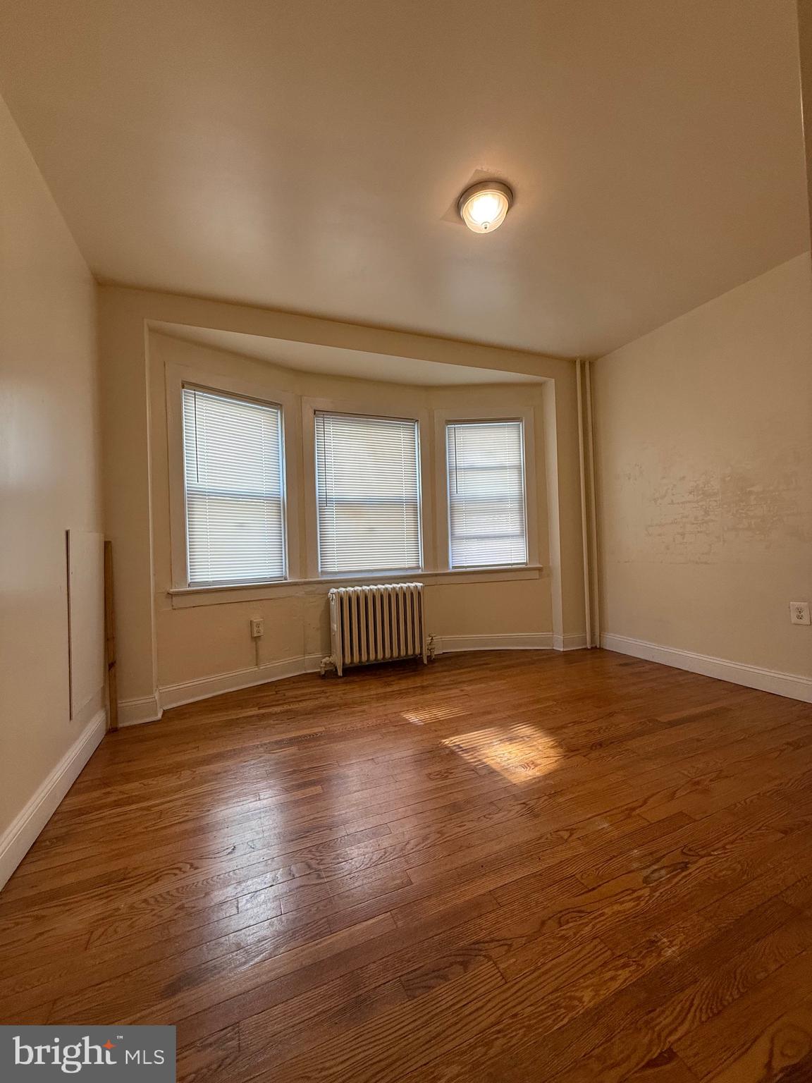 2250 Bryn Mawr Avenue, Unit 1C Philadelphia, PA 19131 - Photo 9 of 12 a view of an empty room with wooden floor and a window