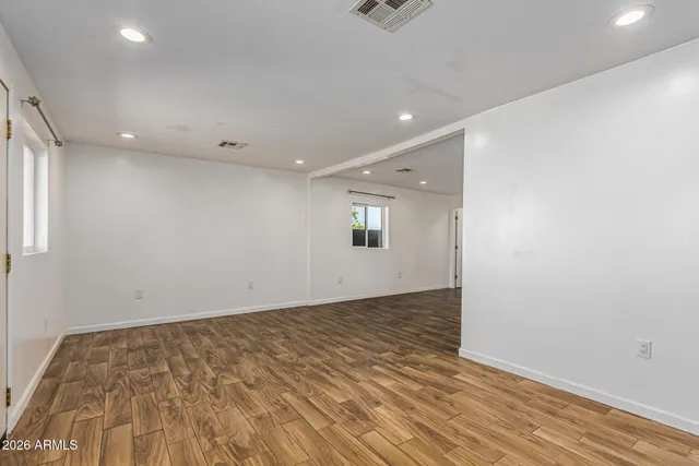 an empty room with wooden floor and windows