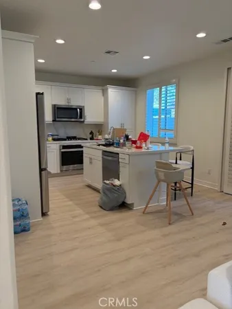 a living room with stainless steel appliances kitchen island granite countertop a sink cabinets and wooden floor