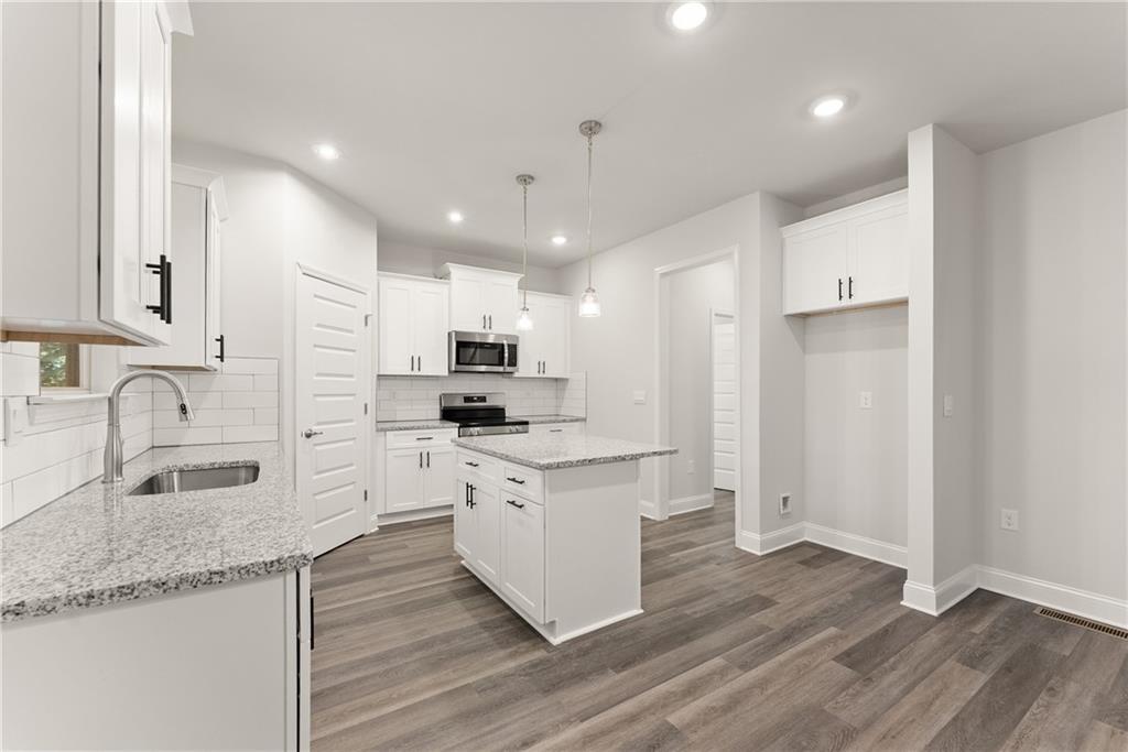 490 Magnolia Grove Place Cornelia, GA 30531 - Photo 12 of 43 a large kitchen with stainless steel appliances granite countertop a stove a sink a refrigerator and white cabinets with wooden floor