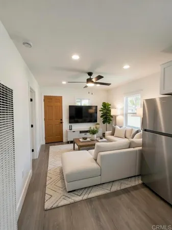a living room with furniture a flat screen tv and a refrigerator