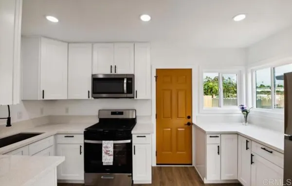 a kitchen with stainless steel appliances a stove microwave and sink