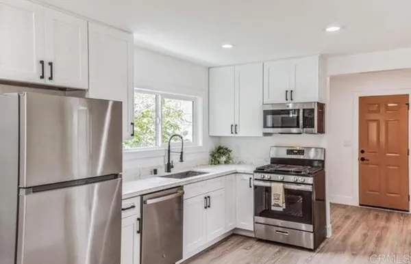 a white kitchen with stainless steel appliances a refrigerator sink and microwave