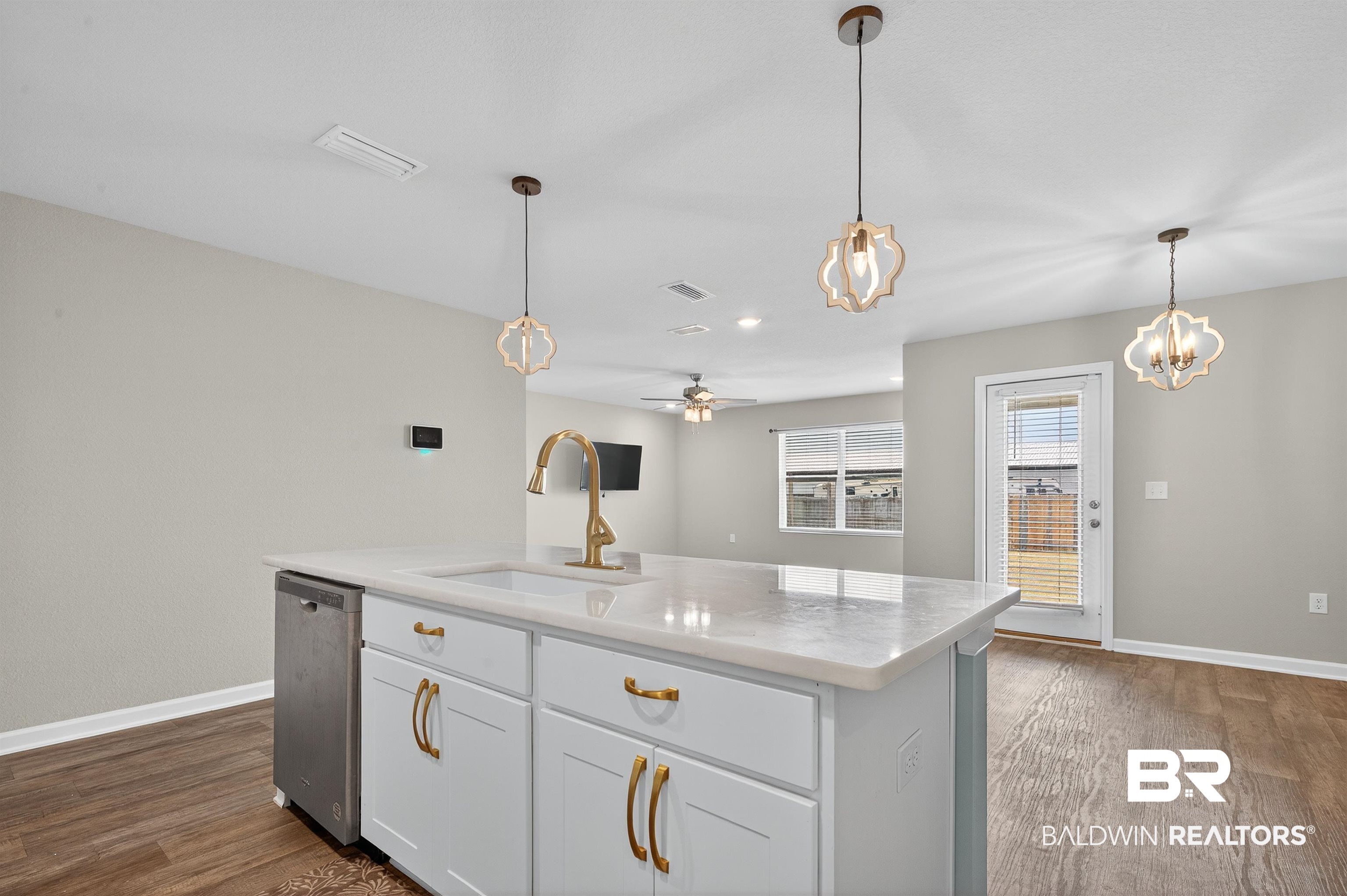 7429 Brompton Drive Foley, AL 36535 - Photo 5 of 50 Kitchen featuring dark wood-style flooring, hanging light fixtures, white cabinetry, a kitchen island with sink, and light stone countertops