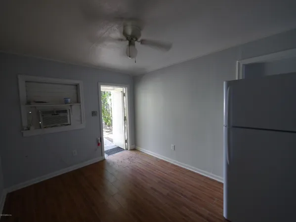 a view of empty room with wooden floor and fan