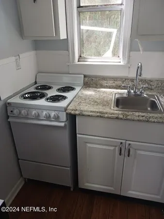a close view of a stove a sink and dishwasher with wooden floor