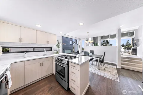 a kitchen with stainless steel appliances granite countertop a stove a sink dishwasher and a refrigerator with wooden floor