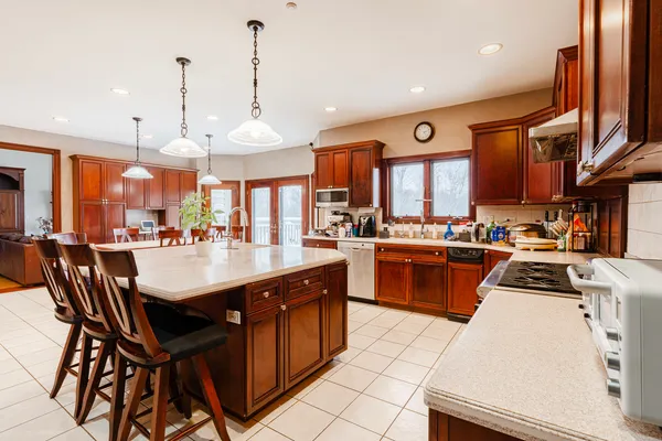 a kitchen with stainless steel appliances granite countertop a stove a sink dishwasher and a refrigerator with wooden floor