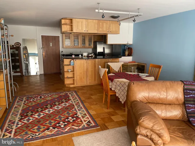 a living room with stainless steel appliances furniture a rug and a kitchen view