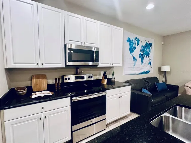 a kitchen with granite countertop a sink dishwasher stove and white cabinets