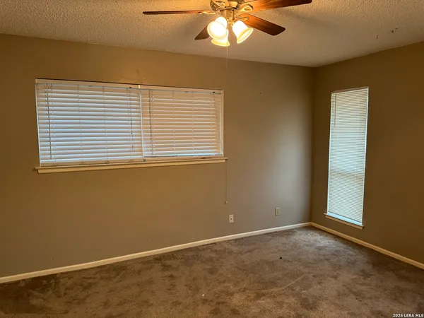 a view of an empty room with a chandelier fan