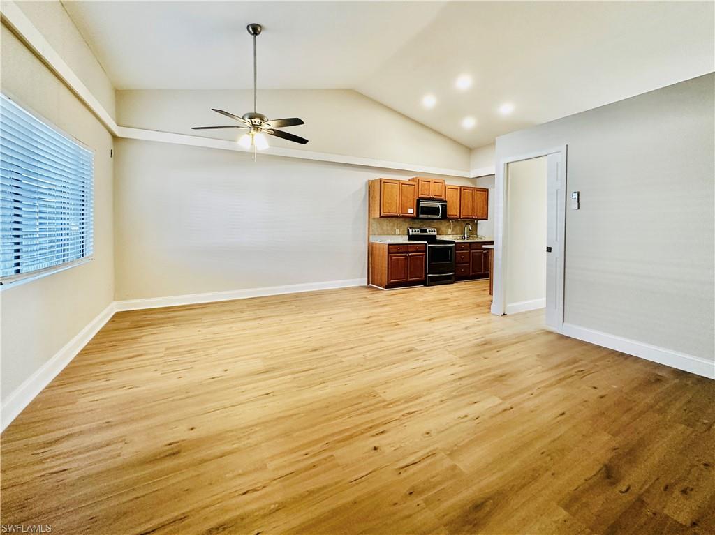 826 Wiggins Pass Road, Unit 310 Naples, FL 34110 - Photo 5 of 18 Kitchen featuring lofted ceiling, light countertops, brown cabinetry, appliances with stainless steel finishes, and light wood finished floors