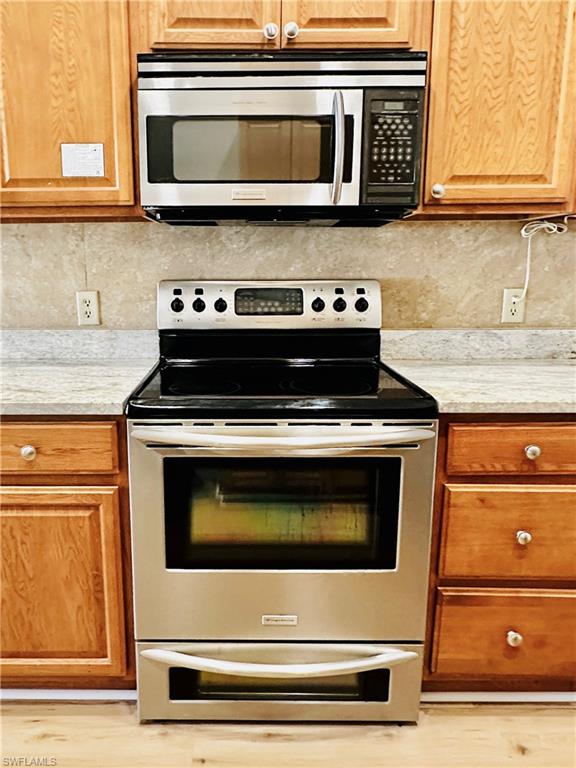 826 Wiggins Pass Road, Unit 310 Naples, FL 34110 - Photo 7 of 18 Kitchen with stainless steel appliances, brown cabinets, and light wood-style floors