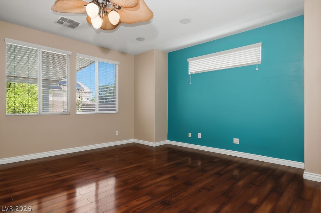 9712 North Running Rabbit Street Las Vegas, NV 89143 - Photo 9 of 42 Rich hardwood flooring complements a vibrant accent wall in this adaptable living space.