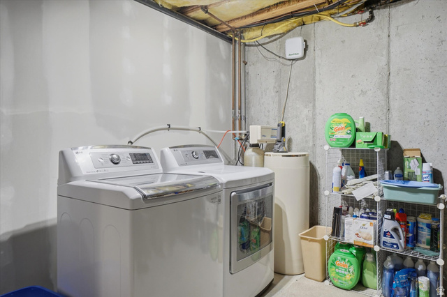 5576 South 4100th Street West Roy, UT 84067 - Photo 31 of 35 Dedicated laundry area featuring a washer and dryer, exposed ceiling joists, and concrete walls