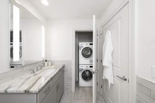 a bathroom with a granite countertop sink and a washing machine