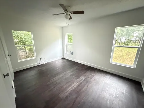 an empty room with wooden floor and windows