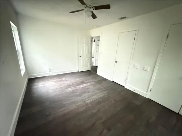 an empty room with a ceiling fan and window