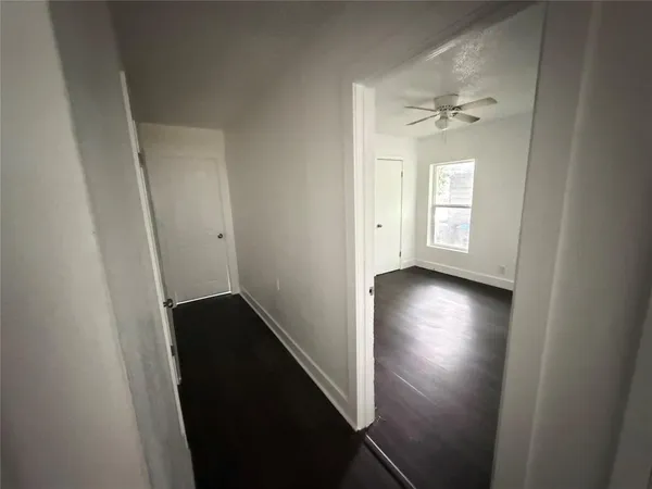 an empty room with wooden floor closet and windows