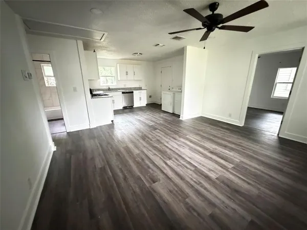a view of a room with wooden floor and a kitchen