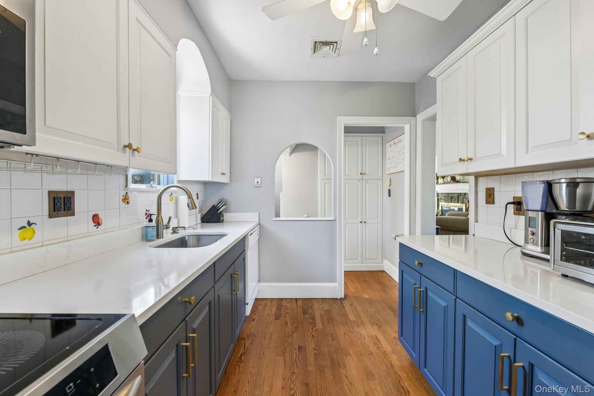 60 Croyden Road Mineola, NY 11501 - Photo 10 of 33 Galley kitchen with two-tone cabinetry, white countertops, stainless steel sink, and wood-finish flooring