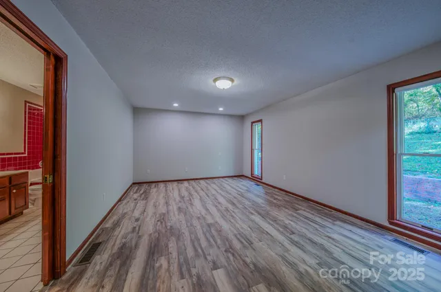 a view of an empty room with wooden floor and window