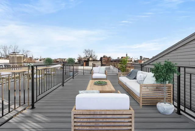 a view of a rooftop deck with couch and chairs