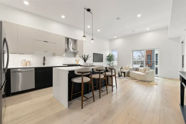 a kitchen with stainless steel appliances kitchen island granite countertop a table chairs sink and cabinets
