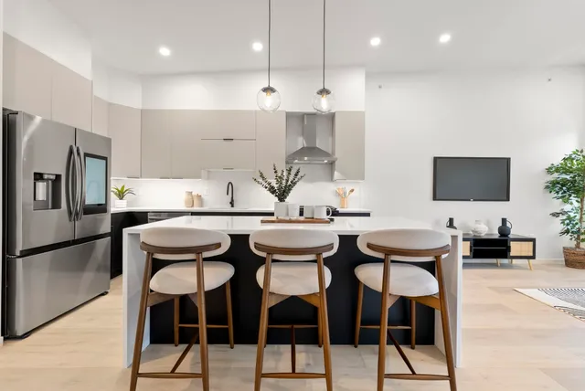 a kitchen with stainless steel appliances kitchen island granite countertop a dining table chairs and a refrigerator