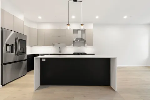 a kitchen with kitchen island a counter space a refrigerator and a cabinets