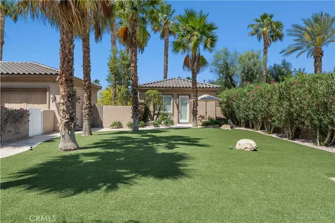 a front view of a house with a yard and palm trees