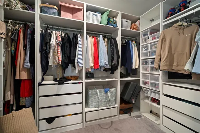 a view of walk in closet with clothes and shoes
