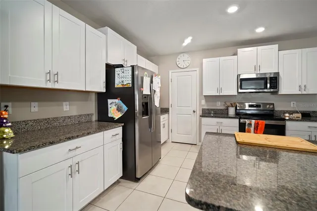 a kitchen with stainless steel appliances granite countertop a stove a sink and white cabinets