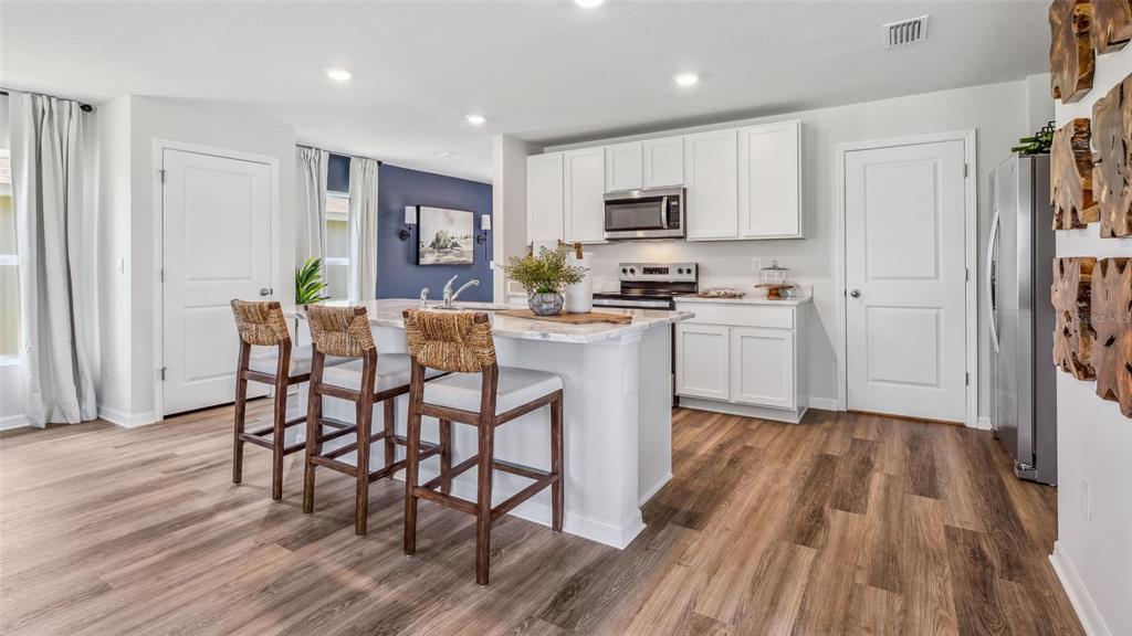 9939 Wimico Terrace Parrish, FL 34219 - Photo 7 of 32 a kitchen with stainless steel appliances a microwave a stove a table and chairs in it